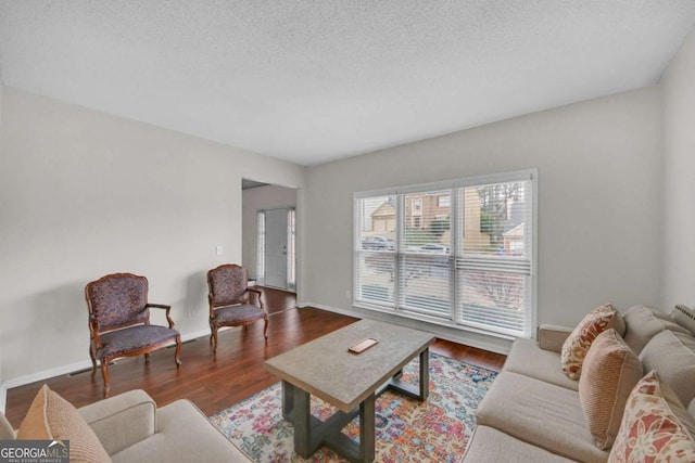 living room with a textured ceiling, wood finished floors, and baseboards