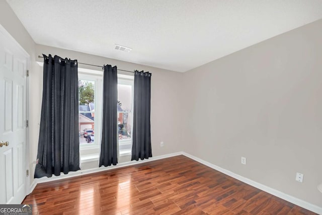 empty room featuring baseboards, visible vents, and wood finished floors