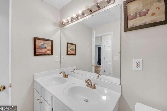 bathroom with a sink, toilet, and double vanity