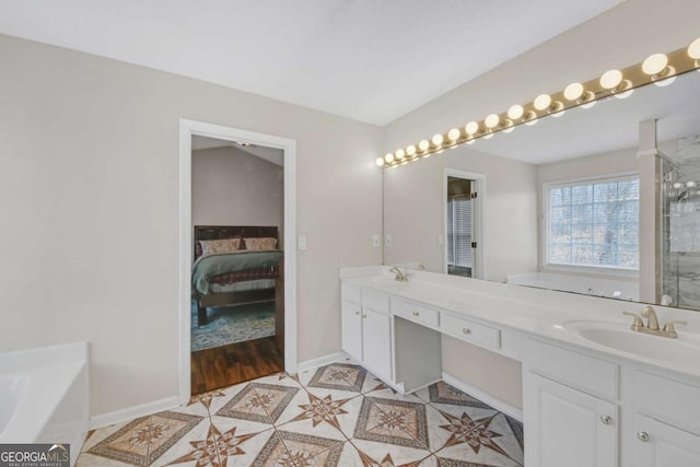 ensuite bathroom with double vanity, baseboards, a bath, a shower with door, and a sink