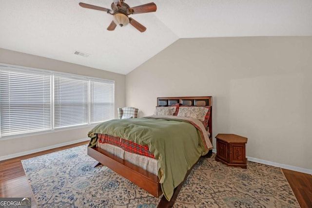 bedroom featuring visible vents, baseboards, a ceiling fan, wood finished floors, and vaulted ceiling