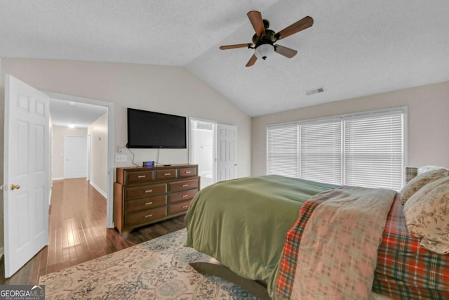 bedroom featuring lofted ceiling, a ceiling fan, visible vents, and wood finished floors