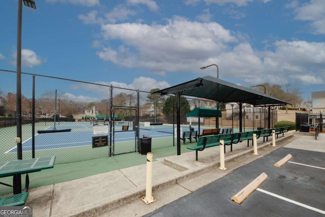 surrounding community with a tennis court, a gate, fence, and uncovered parking