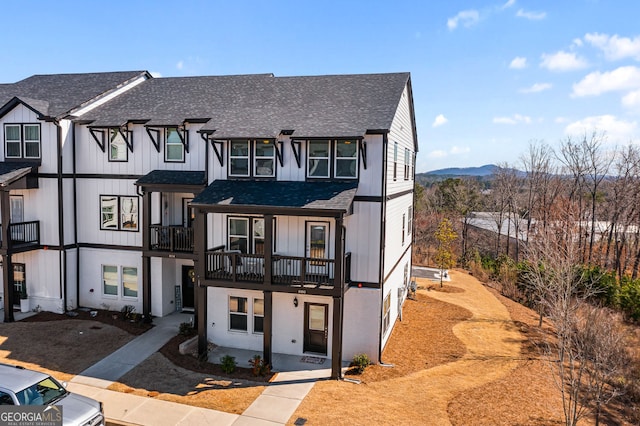 townhome / multi-family property with a shingled roof, a mountain view, and board and batten siding