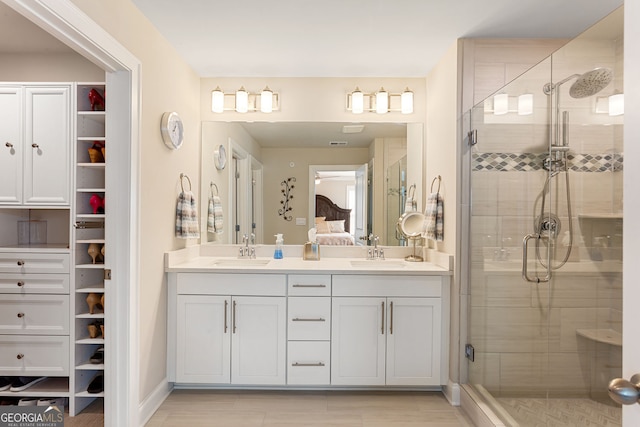 full bath featuring a sink, a shower stall, and double vanity