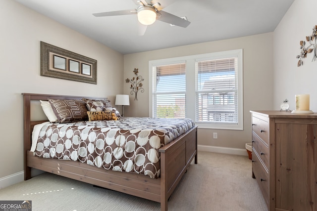 bedroom featuring light carpet, a ceiling fan, and baseboards