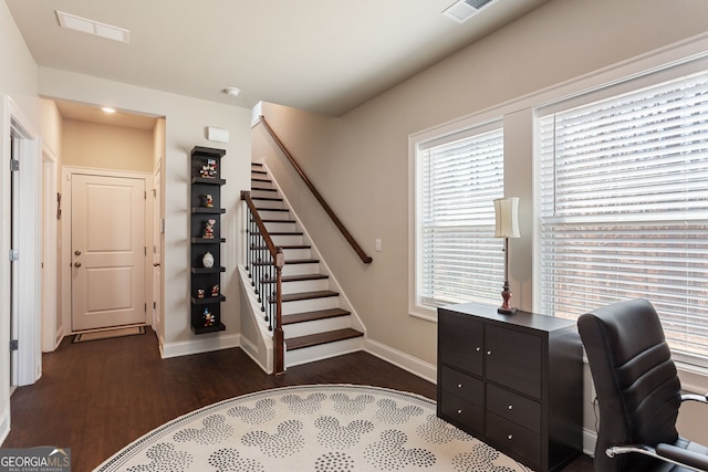 office area with dark wood-style floors, visible vents, and baseboards