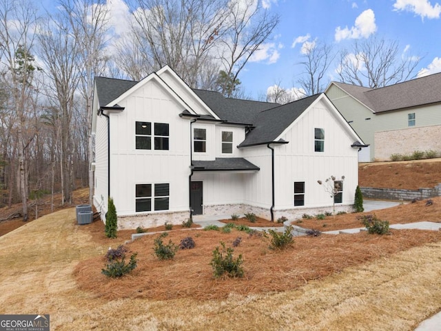 modern farmhouse style home with brick siding, cooling unit, board and batten siding, and roof with shingles