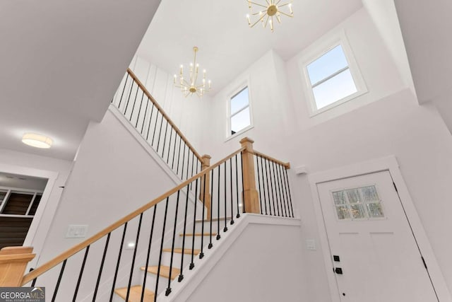 staircase with a high ceiling and an inviting chandelier