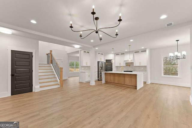 kitchen with light countertops, visible vents, open floor plan, a chandelier, and light wood-type flooring