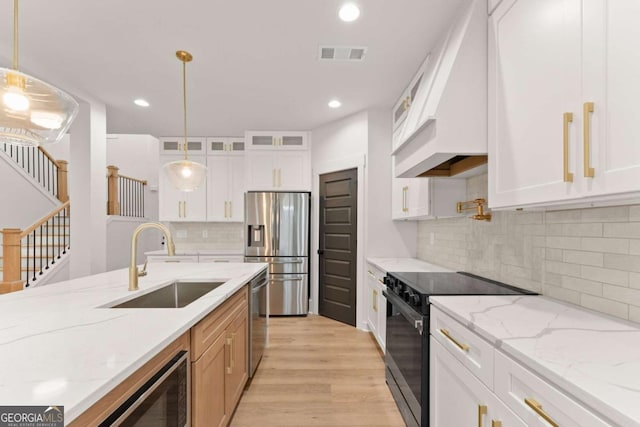 kitchen featuring light wood finished floors, visible vents, glass insert cabinets, appliances with stainless steel finishes, and a sink