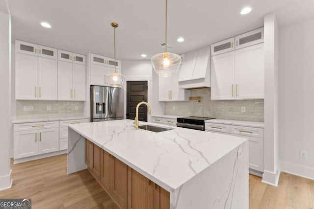 kitchen with stainless steel appliances, light wood-style floors, a sink, and custom range hood