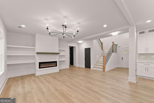 unfurnished living room with light wood-style flooring, stairs, baseboards, and a glass covered fireplace