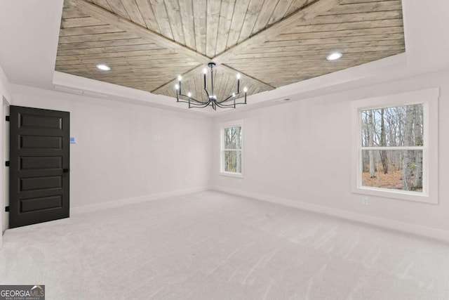 spare room with a notable chandelier, wood ceiling, baseboards, carpet, and a raised ceiling