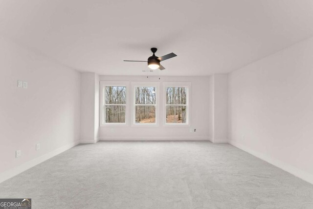 empty room featuring carpet flooring, a ceiling fan, and baseboards