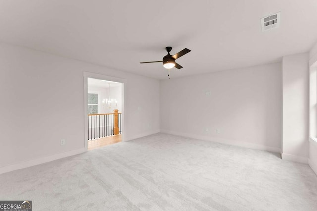 empty room with plenty of natural light, baseboards, visible vents, carpet flooring, and ceiling fan with notable chandelier