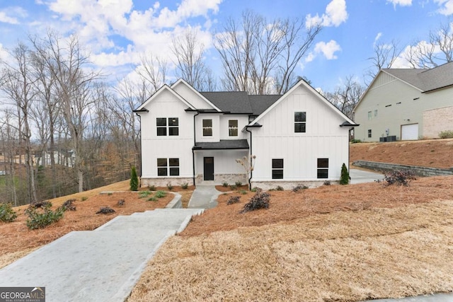 modern farmhouse style home with stone siding, roof with shingles, and board and batten siding