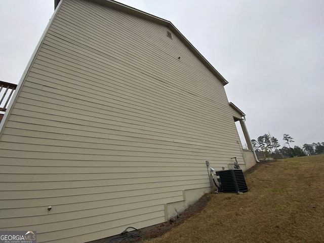 view of property exterior with central AC and a yard