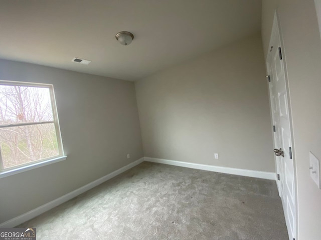 spare room featuring carpet flooring, visible vents, and baseboards