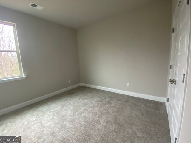 unfurnished bedroom featuring multiple windows, carpet flooring, visible vents, and baseboards