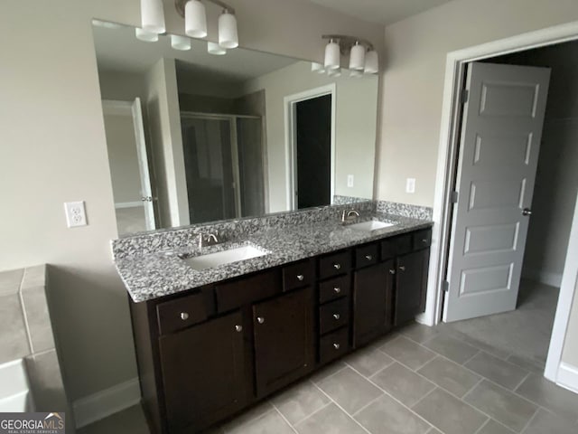 full bathroom with double vanity, a stall shower, a sink, and tile patterned floors