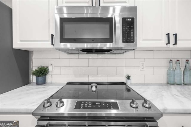 kitchen featuring light stone countertops, white cabinetry, appliances with stainless steel finishes, and backsplash