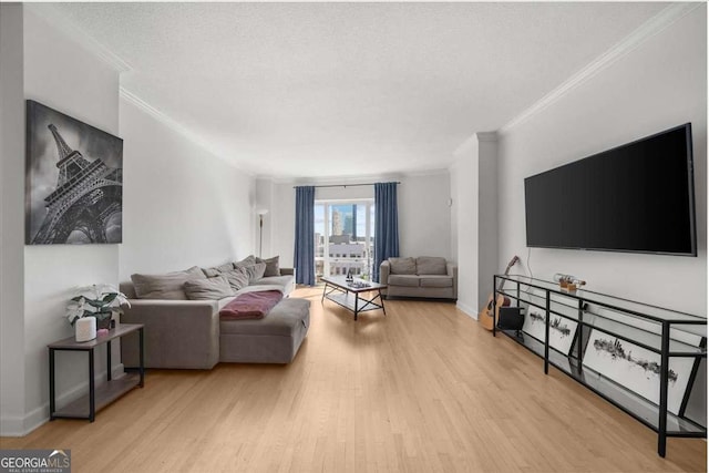 living room with a textured ceiling, ornamental molding, wood finished floors, and baseboards