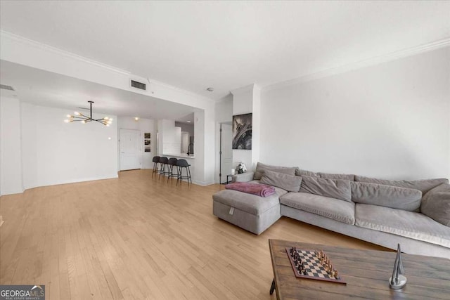 living area with ornamental molding, light wood finished floors, visible vents, and a notable chandelier