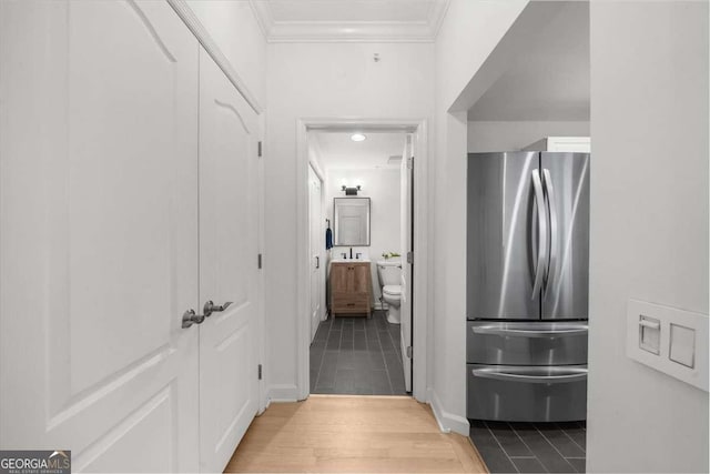 hallway with light wood-type flooring and crown molding