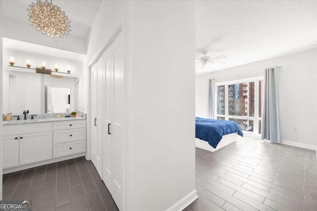 bathroom with ceiling fan, baseboards, wood finish floors, and vanity