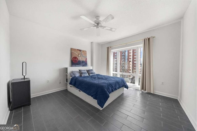 bedroom featuring a textured ceiling, baseboards, dark wood finished floors, and a ceiling fan