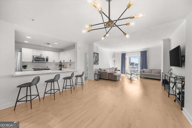 kitchen with white cabinets, decorative backsplash, a breakfast bar, stainless steel appliances, and a sink