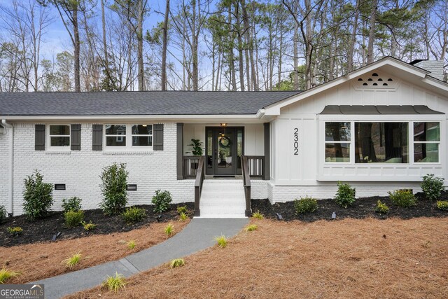 view of front of property with brick siding, a shingled roof, driveway, crawl space, and board and batten siding