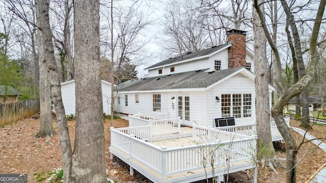 back of house featuring a shingled roof, fence, a chimney, and a wooden deck