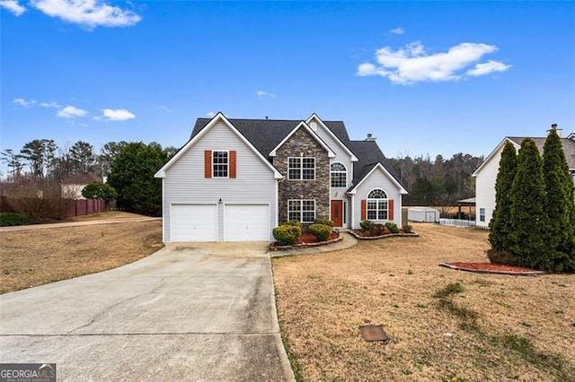 traditional home with driveway, stone siding, an attached garage, fence, and a front yard