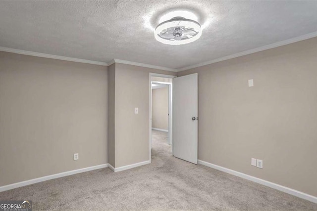 empty room with ornamental molding, carpet, a textured ceiling, and baseboards