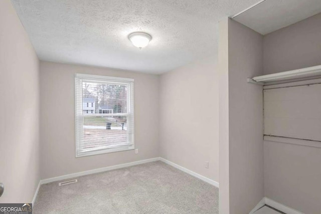 interior space featuring visible vents, a textured ceiling, baseboards, and carpet flooring