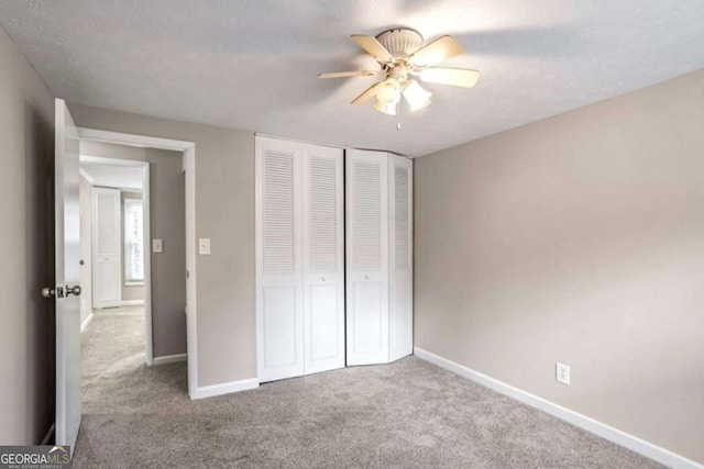 unfurnished bedroom with carpet floors, ceiling fan, baseboards, and a closet