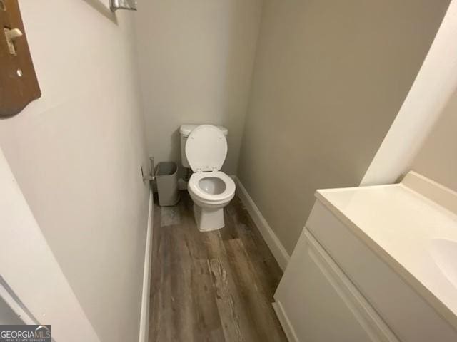 bathroom with baseboards, vanity, toilet, and wood finished floors