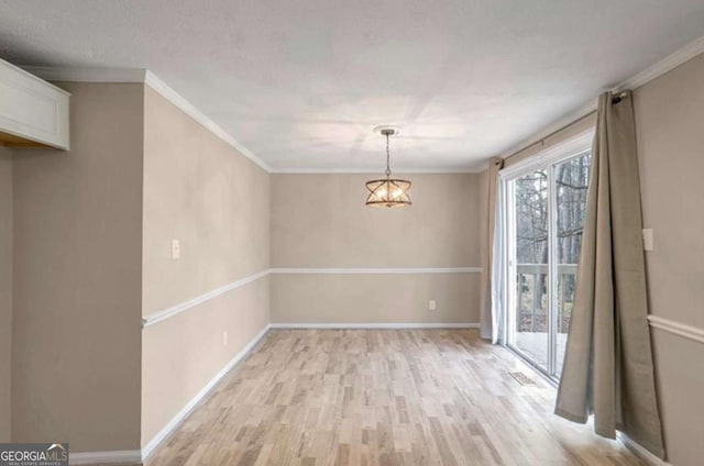 unfurnished dining area with a notable chandelier, ornamental molding, light wood-type flooring, and baseboards