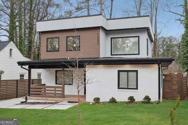 view of front of house with brick siding, fence, and a front lawn