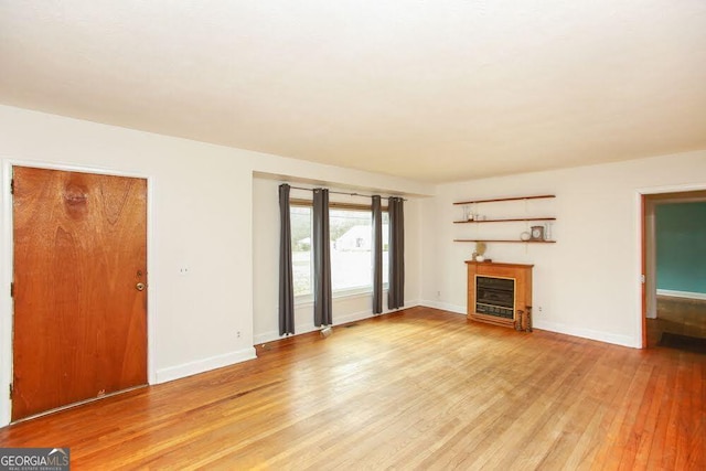 unfurnished living room with light wood-type flooring, a fireplace, and baseboards