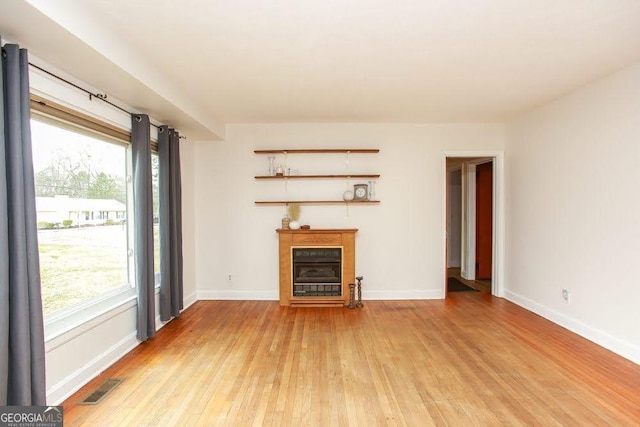 unfurnished living room with light wood-style flooring, visible vents, and baseboards