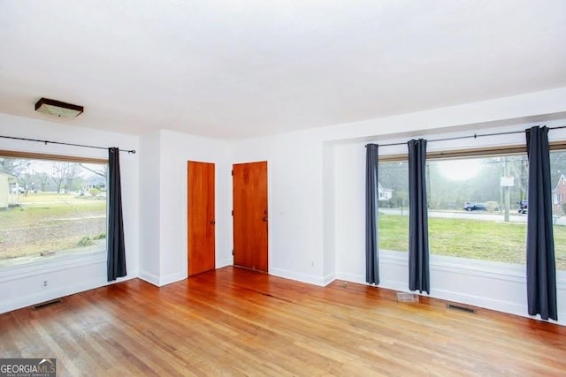 interior space with wood finished floors, visible vents, and baseboards