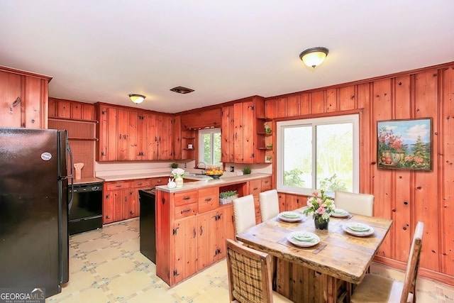 kitchen featuring light floors, a peninsula, light countertops, black appliances, and open shelves