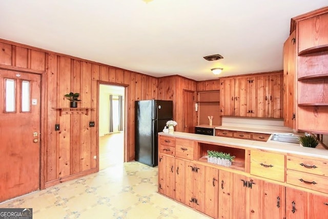 kitchen featuring wooden walls, freestanding refrigerator, light countertops, light floors, and open shelves