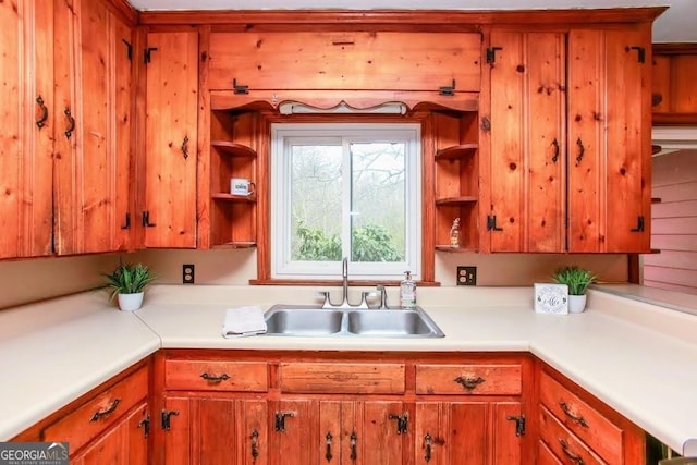 kitchen with brown cabinetry, light countertops, a sink, and open shelves