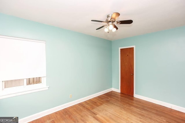 unfurnished room with wood finished floors, a ceiling fan, and baseboards