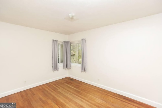 empty room featuring light wood finished floors and baseboards