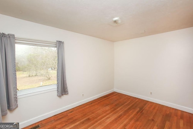 empty room with baseboards and wood finished floors